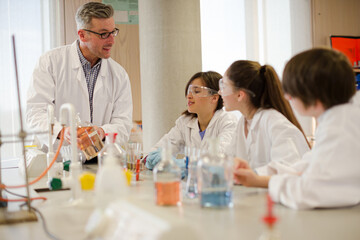 Male teacher and students conducting scientific experiment in laboratory classroom