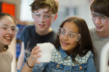 Students watching chemical reaction, conducting scientific experiment in laboratory classroom
