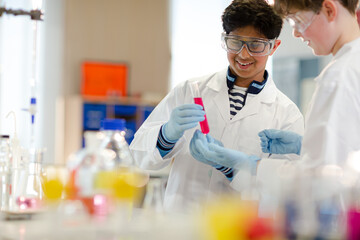 Boy students examining liquid in test tube, conducting scientific experiment in laboratory classroom