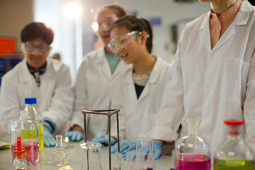 Female teacher and students watching scientific experiment chemical reaction in laboratory classroom