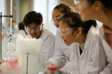 Female teacher and students watching scientific experiment chemical reaction in laboratory classroom