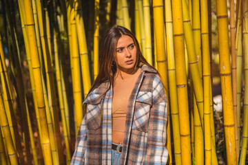 Autumn lifestyle in a bamboo forest, sweet look of a young brunette in a plaid wool sweater