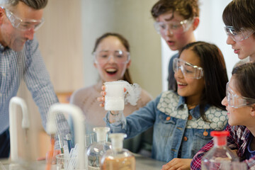 Male teacher and students watching chemical reaction, conducting scientific experiment in laboratory classroom
