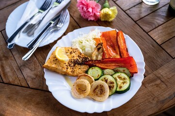 Zander fish and grilled vegetable on first plate, second plate with cutlery.
