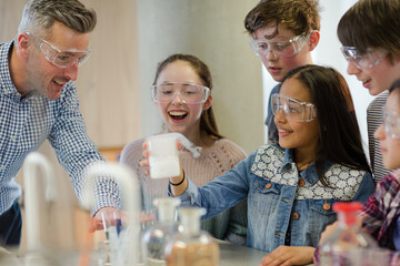 Male teacher and students watching chemical reaction, conducting scientific experiment in...