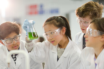 Curious students conducting scientific experiment, examining liquid in beaker in laboratory...