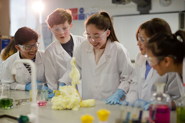 Surprised students conducting exploding foam scientific experiment in classroom laboratory