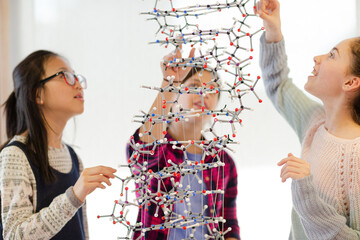Curious girl students examining molecular structure in classroom