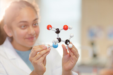 Curious girl student examining molecular structure in laboratory classroom