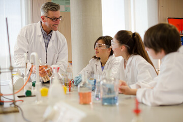 Male teacher and students conducting scientific experiment in laboratory classroom