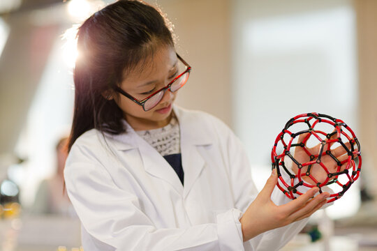 Portrait smiling, confident girl student holding molecular structure in laboratory classroom