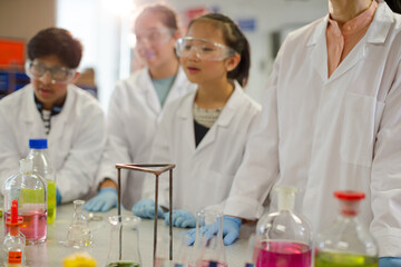 Fototapeta premium Female teacher and students watching scientific experiment chemical reaction in laboratory classroom