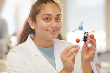 Curious girl student examining molecular structure in laboratory classroom