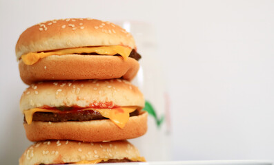 Pile of cheeseburgers on white background.