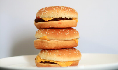 Pile of cheeseburgers on white background.