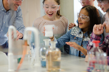 Male teacher and students watching chemical reaction, conducting scientific experiment in...