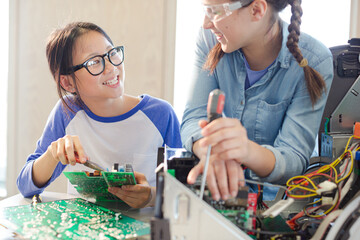 Girl students assembling computer in classroom