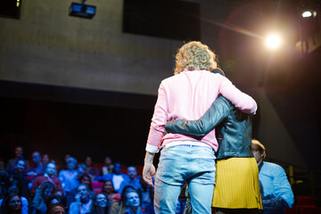 Fototapeta na wymiar Speakers hugging on stage for audience at conference