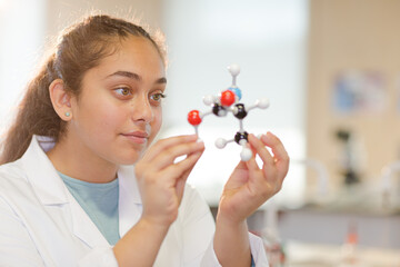 Curious girl student examining molecular structure in laboratory classroom