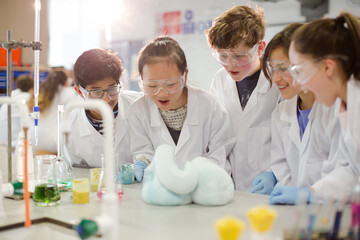 Surprised students conducting exploding foam scientific experiment in classroom laboratory