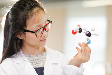 Portrait smiling, confident girl student holding molecular structure in laboratory classroom