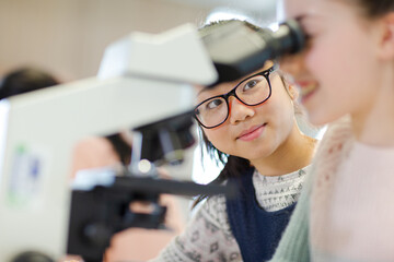 Close up profile girl student using microscope, conducting scientific experiment