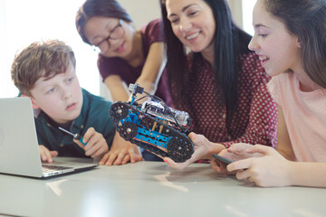 Fototapeta premium Female teacher and students playing with robot in classroom