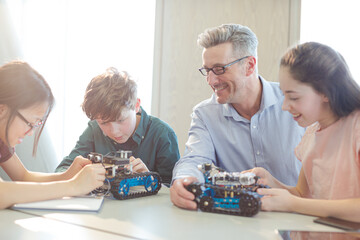 Male teacher and students playing with robot in classroom