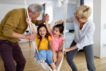 Portrait of happy elderly couple and grandchildren playing together