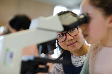 Close up profile girl student using microscope, conducting scientific experiment