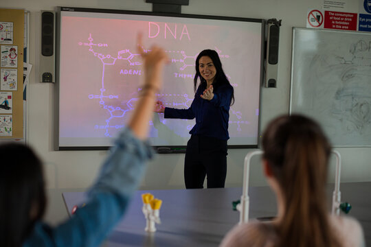 Female science teacher teaching DNA lesson at projection screen