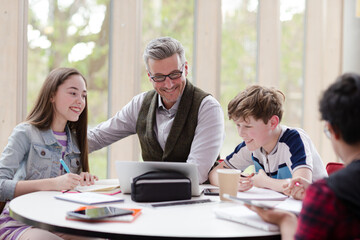 Fototapeta premium Male teacher and students using laptop at table