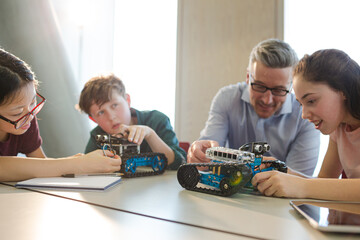 Male teacher and students playing with robot in classroom