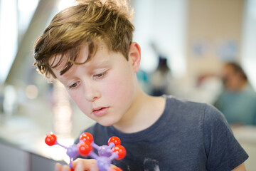 Curious boy examining molecule model in laboratory classroom