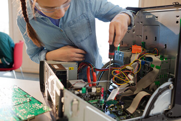 Girl student assembling computer in classroom