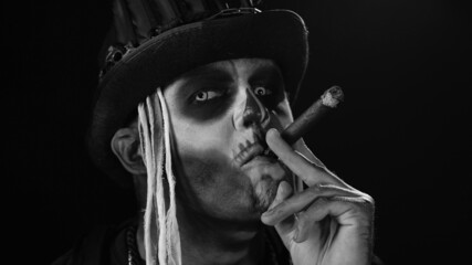 Close-up shot of sinister man with Halloween holiday skeleton makeup in costume raising his head...