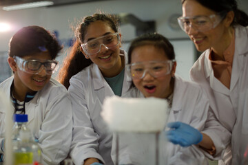 Fototapeta na wymiar Female teacher and students watching scientific experiment chemical reaction in laboratory classroom