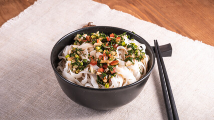 Korean rice noodles with spicy herb sauce in a bowl on the table covered with a napkin with chopsticks