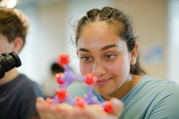 Curious girl examining molecule model in classroom