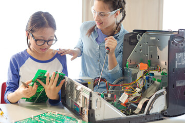 Girl students assembling computer in classroom