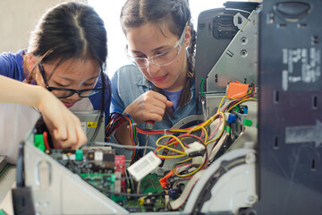 Girl students assembling computer in classroom