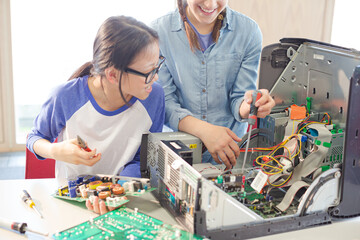 Girl students assembling computer in classroom