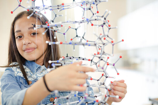 Portrait smiling girl student holding molecular model in laboratory classroom