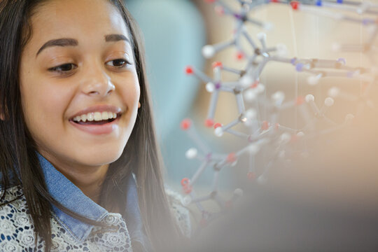 Portrait smiling girl student holding molecular model in laboratory classroom