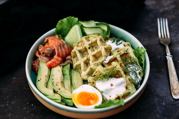 Belgian waffles with salmon, avocado and egg in a plate