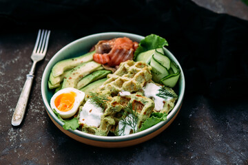 Belgian waffles with salmon, avocado and egg in a plate