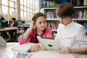 Students using digital tablet in library