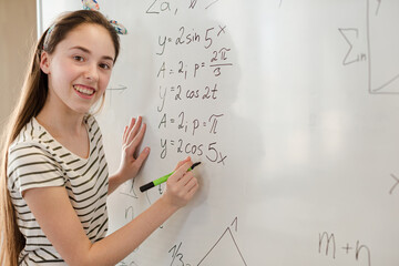 Fototapeta premium Girl student writing at whiteboard in classroom