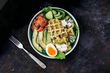 Belgian waffles with salmon, avocado and egg in a plate