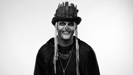 Sinister man with horrible Halloween skeleton makeup in costume with top-hat making faces, looking...